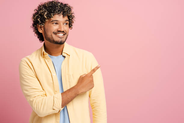 istock Young man pointing and smiling on pink background 2166513445