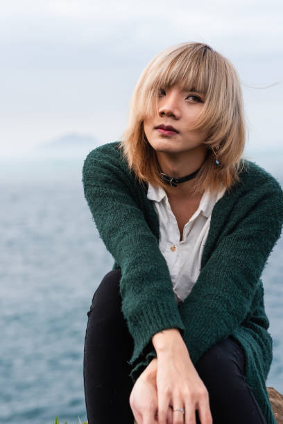 istock A non-Binary person sitting on the rock by the sea 2166520644