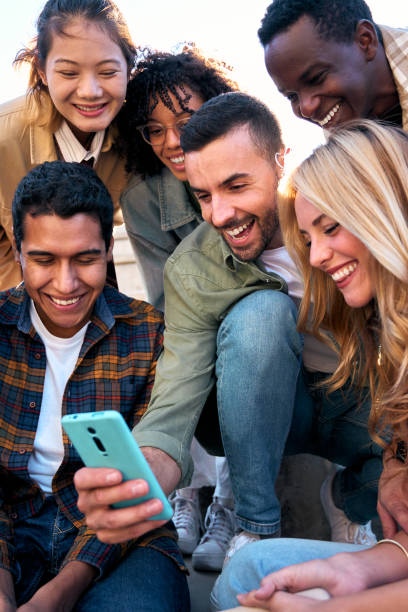 istock Group of young people watching something at and using phone sitting on stairs. Students lifestyle 2166520702