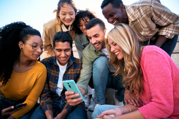 istock Group of young people watching something at and using phone sitting on stairs. Students lifestyle 2166522546