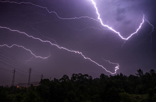 istock Thunderstorm night with several rays in the sky over the tree line on the horizon. 2166522713
