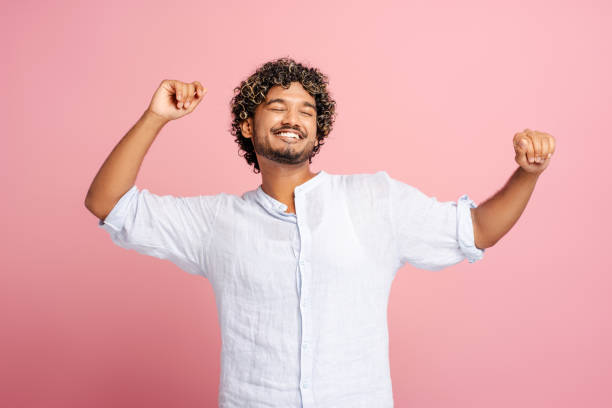istock Attractive Indian man smiling and stretching arms on pink background 2166530929