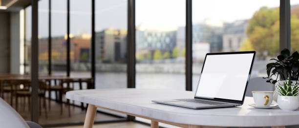 istock A laptop on a table by the window with a city view, in a contemporary office co-working space. 2166535366