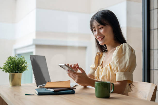 istock A beautiful Asian woman using her smartphone at her desk, using her smartphone while working. 2166535644