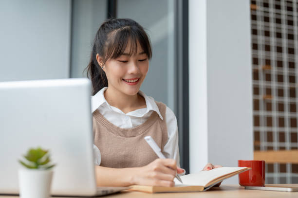 istock An Asian female college student is lecturing in a book while studying an online class via her laptop 2166535727
