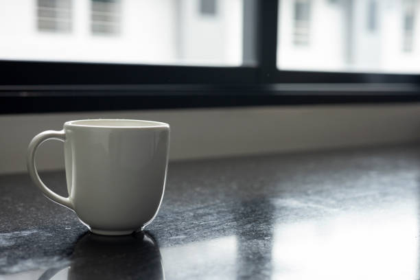 Minimalist White Ceramic Coffee Cup: Empty and Clean, Resting on a Table with Morning Light Reflecting Through a Window.