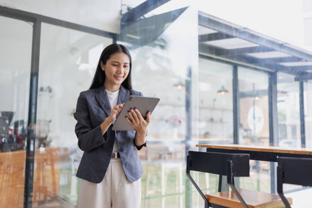 istock Smiling  asian woman holding a tablet standing in office. 2166553398