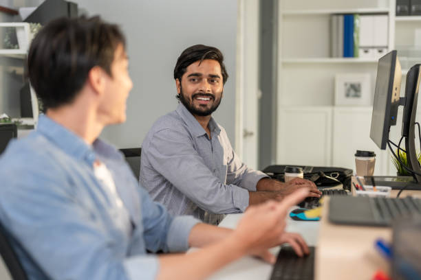 istock Asian two handsome businessman working with team in office workplace. Attractive professional male employee worker sitting on table, feel happy and enjoy spending leisure time in corporate workplace. 2166554141