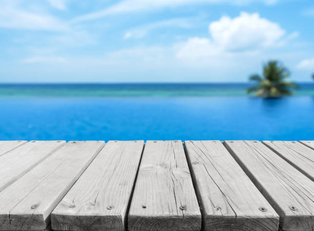istock Wooden platform beside tropical infinity swimming pool 2166557394