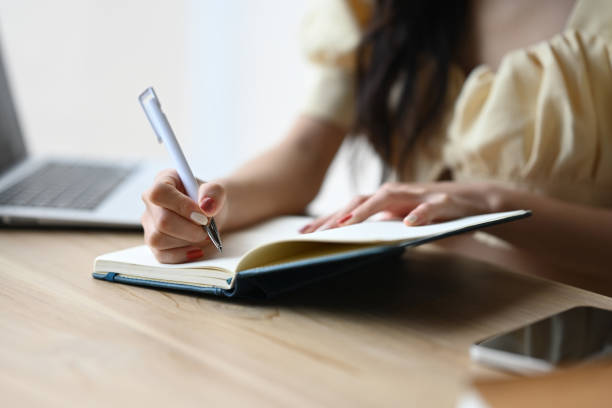istock Smiling young woman writing notebook, planning ideas on paper notes at office desk 2166558275