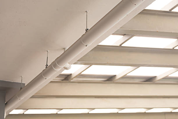 The white duct system is mounted on the white ceiling under the roof.