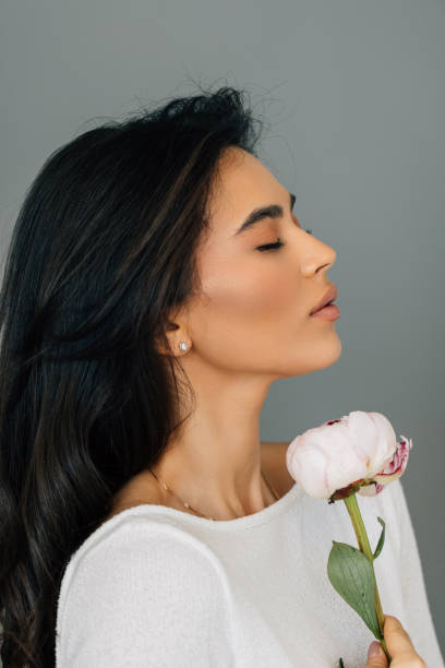 istock Young woman posing with peony flower over white background 2166563236