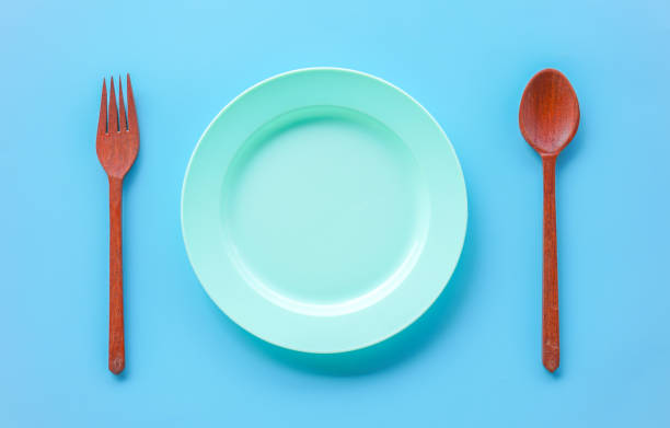 istock Top view of empty green plastic dish with wood spoon and fork on blue background 2166565070