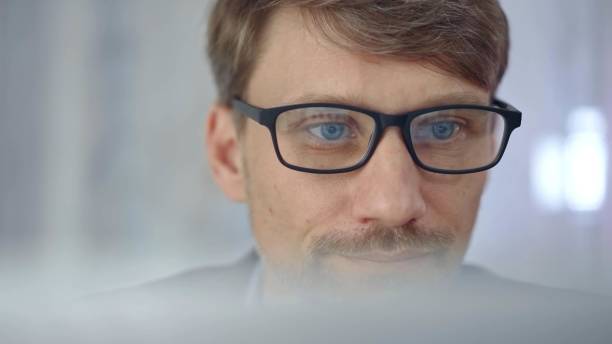 istock Businessman with glasses looking intently obscured partially by a translucent surface of laptop. Business concept 2166566621