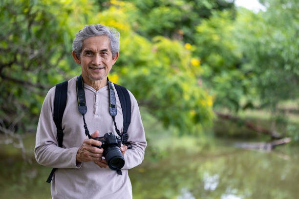 istock Asian senior man is trekking in the forest while using camera to take memorable photo for elder exercise outdoor and nature environment therapy 2166567640