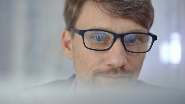 istock Businessman with glasses looking intently obscured partially by a translucent surface of laptop. Business people concept 2166567673