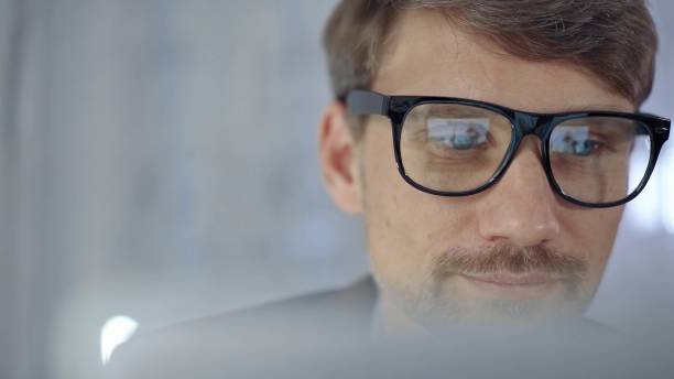 istock Businessman with glasses looking intently obscured partially by a translucent surface of laptop. Business people concept 2166567748