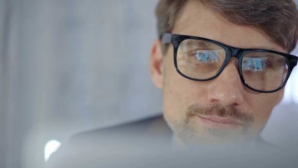istock Businessman with glasses looking intently obscured partially by a translucent surface of laptop. Business people concept 2166567893