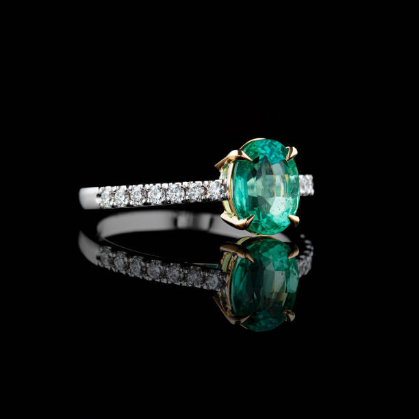 istock Beautiful white gold ring with diamonds and emerald on a black background 2166569793