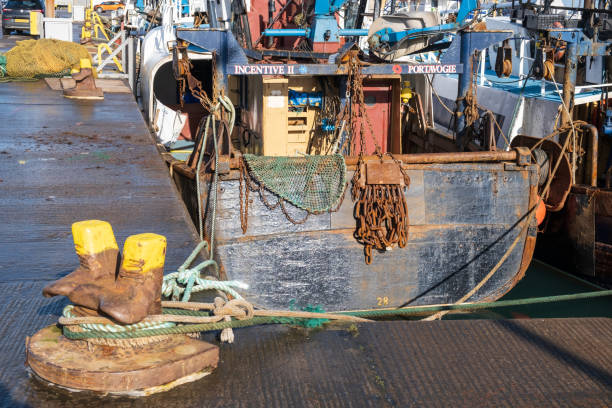 Portavogie, UK - February 22nd, 2022: Fishing boat moored along the quay side harbour with mooring point in shape of a pair of boots.