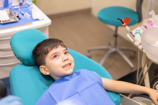 istock kid in dental office. dentist checking child teeth using tools mouth mirror and scalar.crying with tears, sad boy is afraid.doctor looking at screen,tooth filling treatment.kid in chair being examined 2166570442