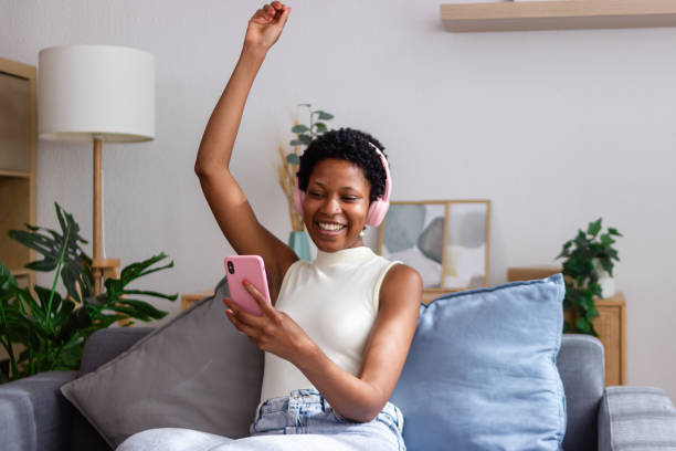 istock Happy young woman is using a smartphone while sitting on a comfortable sofa at home 2166571518