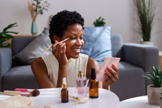 istock Beautiful black woman applying makeup at home using brush 2166572058