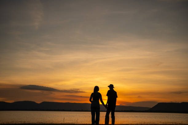 istock A couple standing on a beach at sunset, holding hands 2166572535