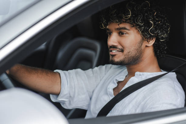 istock Smiling handsome Indian man driving car smiling and looking away 2166572570