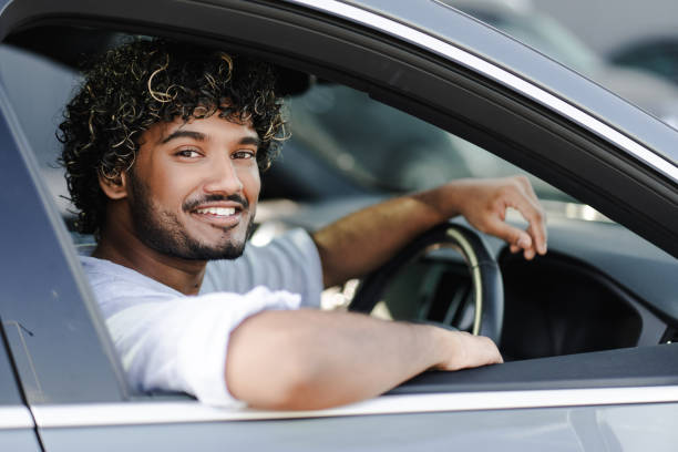 istock Handsome Indian young man smiling while driving his new car 2166572584