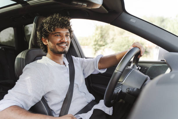 istock Smiling, Indian man smiling while driving modern car in the city 2166572601