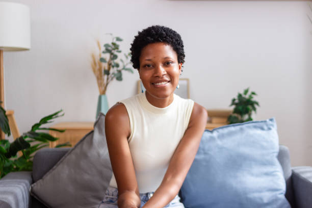 istock Young black woman smiling sitting on sofa at home 2166573478