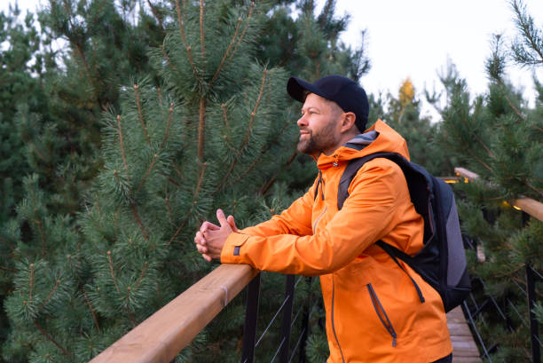 Man with backpack and orange jacket enjoying nature in scandinavian forest