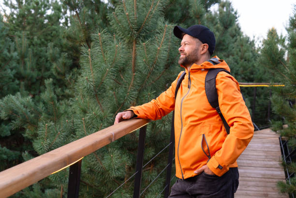 istock Man with backpack and orange jacket enjoying nature in scandinavian forest 2166575050