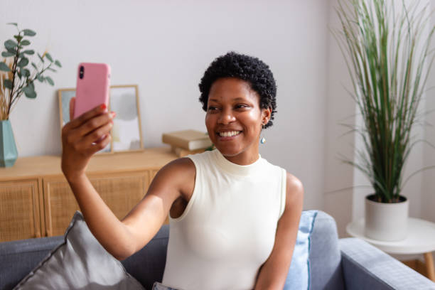 istock Young black woman smiling while taking a selfie on the couch 2166576614