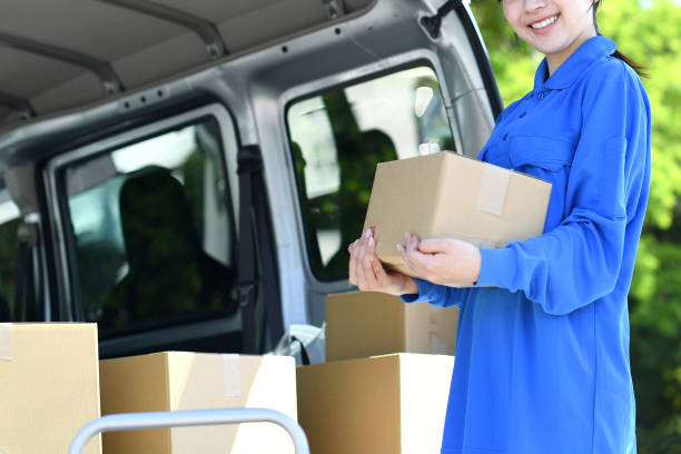 istock An Asian female delivery driver is smiling and looking at the camera while holding a package. 2166577765