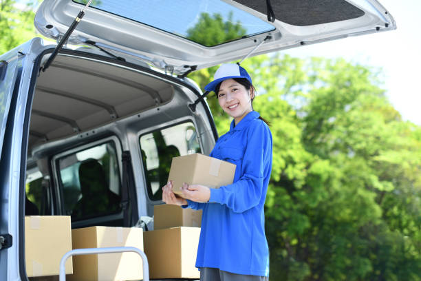 istock An Asian female delivery driver is smiling and looking at the camera while holding a package. 2166578258