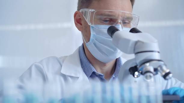 istock Man scientist with protective glasses, mask and gloves is using microscope in laboratory, portrait of researcher. Microbiology science concept 2166581004