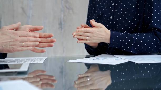 Unrecognizable business people shaking hands and clapping over glass table after contract signing in office. Agreement and handshake themes