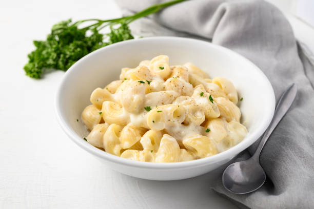 istock Macaroni cheese in bowl with spoon on white background 2166583221