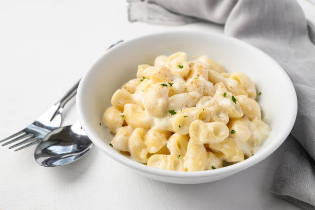 istock Macaroni cheese in bowl with spoon and fork on white background 2166583234
