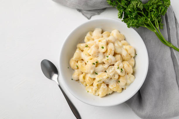 istock Macaroni cheese in bowl with spoon on white background, Top view 2166583243