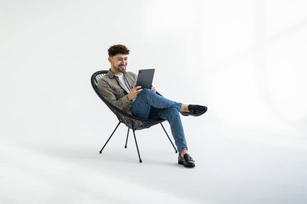 istock Businessman with a tablet, sitting on a chair, white background. 2166583598