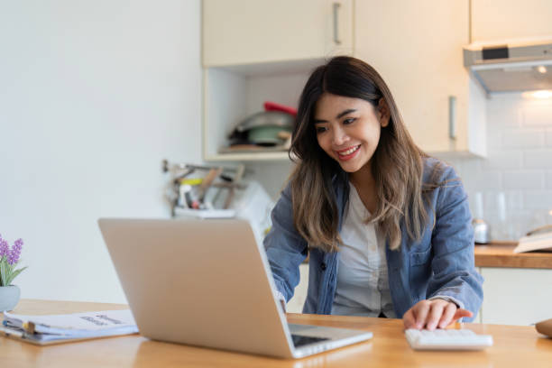 istock Young Woman Working as a Freelancer from Home on Laptop in Modern Kitchen Setting, Smiling and Engaged in Her Work 2166583616