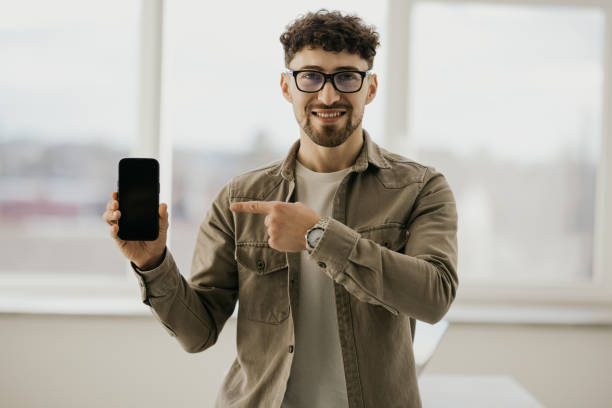 istock Confident man showing mobile phone blank white screen mockup to camera standing isolated 2166583669