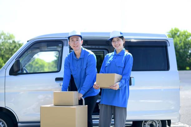 Asian male and female delivery drivers smile and carry packages Asian male and female delivery drivers smile and carry packages mover delivery person box hand truck stock pictures, royalty-free photos & images