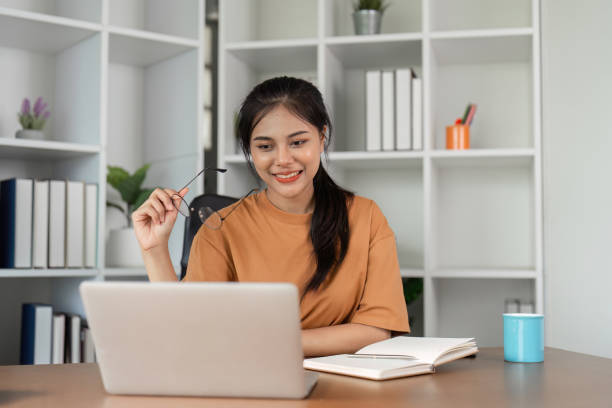 istock Young Woman Studying Online from Home with Laptop and Notebook in Modern Home Office Setting 2166583847