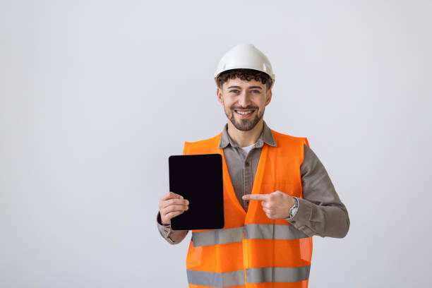istock Smiling male worker or builder in yellow helmet and overall with tablet pc computer over white background 2166583989