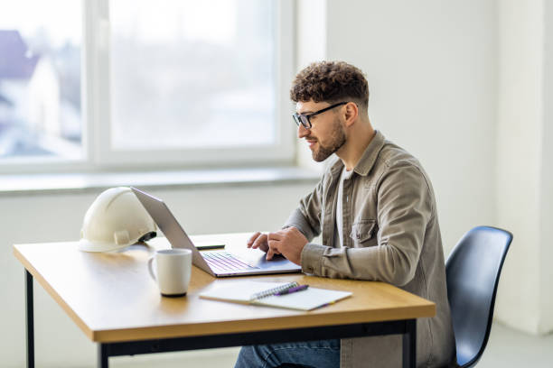 istock Young man working at home with laptop and papers on desk 2166584446