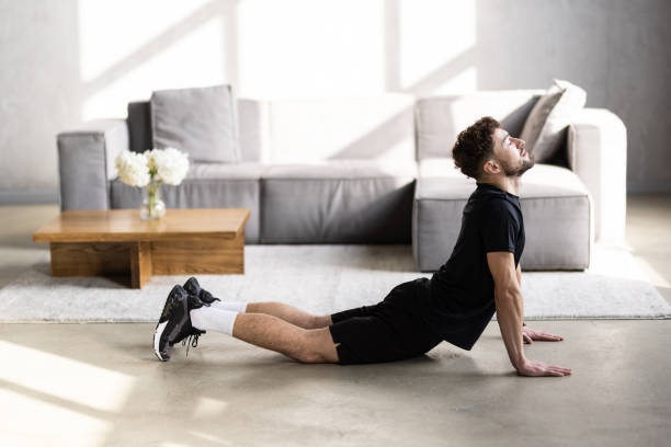 istock Man practicing yoga while watching online class at home during coronavirus pandemic. 2166585088